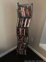 Front angle view of the DVD rack filled with DVDs on six shelves against a wall.
