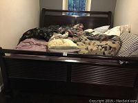 Full view of dark wood sleigh bed frame with bedding and pillows