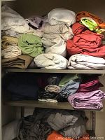 View of shelves with various folded linens including sheets and pillowcases in multiple colors and patterns