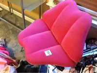 Side view of pink lip-shaped upholstered chair with tubular metal legs, showing the seat and artistic lip design.