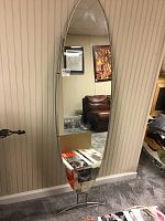 Full view of the tall oval mirror on silver metal stand in a carpeted room.