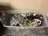 Top-down view of bin showing sealed bags, loose pieces, and instruction booklets along left side