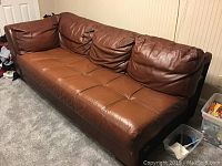 Side perspective of the brown leather sectional sofa piece showing full length and cushioning detail.