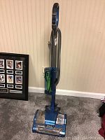 Front view of blue Shark upright vacuum cleaner showing the cleaner head, dustbin, and handle.