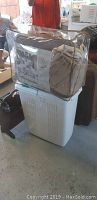 Packaged comforter set on top of white laundry basket.