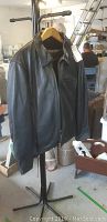 Black leather motorcycle jacket hanging on metal coat rack