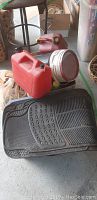 Photo of red gas can, round car light or reflector, and black rubber car floor mats showing texture and design.