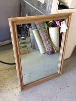 Front view of the wall mounted mirror showing wooden frame and clear reflective glass.