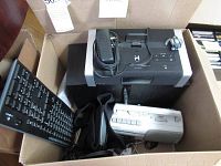 Top view of the box showing the iHome iA100 docking FM clock radio, Energy speakers, Logitech keyboard, Sony portable CD player, and wired headphones inside packed in a cardboard box.