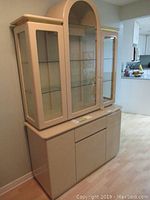Photo showing full buffet and hutch set, beige laminated wood with glass doors and shelves