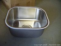 Close-up photo of one stainless steel sink showing rectangular shape with rounded edges and central drain hole