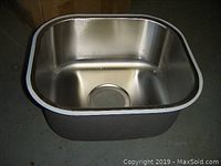 Photo of single stainless steel sink showing rectangular basin, rounded corners and drain hole.