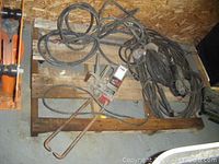 Overall view of spot welding head, electrode arms and coiled cable on wooden pallet