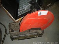 Side angle photo of the orange blade guard and metal base of the cut-off saw