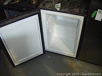 Open fridge door interior showing no shelves inside, white plastic liner