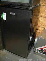 Closed view of black Cuisinart bar fridge showing front and sides with no visible damage.