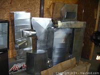Photo showing various pieces of galvanized steel HVAC duct work labeled Stealth Edition Air Box4 including multiple sizes and shapes such as rectangular and square pieces.