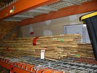 One metal shelf holding multiple bundles of bamboo poles secured with red tape and green ties.