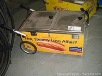 Front‐side view of yellow hot dog cart showing wheels, handles, dual compartments and National Deli graphics.