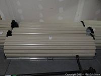 Three beige corrugated steel roll-up doors stacked horizontally against a drywall wall.