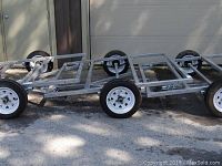 Full side view of galvanized steel trailer frame showing overall structure and four wheels