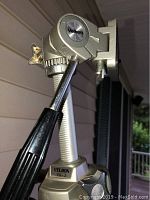 Close-up photo of the pan-and-tilt head of a silver Velbon VG-3 camera tripod showing the adjustment handle and brand label at the top.