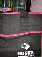 Close-up of black Husky tool holder with red trim and logo, showing fabric and handle.