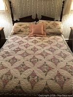 Full size vintage wooden bed frame with headboard, footboard, quilted floral patterned bedspread, pillow shams and throw pillow.