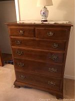 Front view of Ethan Allen wooden chest of drawers showing six drawers and brass handles.