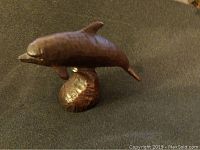 Front left angle view of the wooden dolphin figurine showing the sleek shape and base.