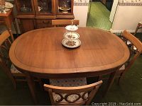 Oval wood dining table with six matching chairs set around it with décor on table.