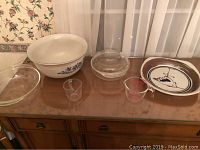 Photo showing entire collection including bowls, plates, and measuring cups arranged on wooden furniture.