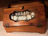 Front view of the solid pine breadbox showing glass panel with floral and word BREAD decoration and knob.