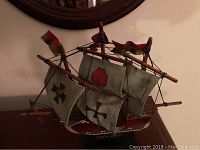 Front and side views of the wooden pirate ship model on its display stand with visible sails and rigging.