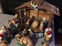 Full view of the nativity scene arranged around the wooden manger, showing majority of figurines and animals in colorful detail.