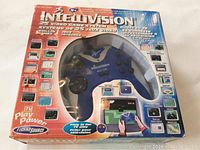 Front view of boxed Intellivision Direct-to-TV system, showing blue controller and game list on packaging