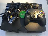Original Xbox console with controller and bundled cables placed on top