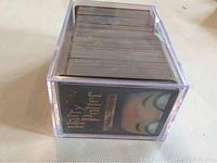 Side view of a large clear lucite box filled with a thick stack of Harry Potter trading cards showing the card back design with the Harry Potter logo.