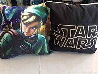 Both cushions shown together on surface: a colorful Link graphic cushion and a black Star Wars logo cushion.