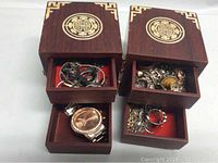 Jewelry box opened to reveal drawers filled with assorted jewelry and men's watch