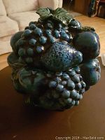 Front view of ceramic blueberry cookie jar showing blueberry cluster design and green leaf lid on a dark surface.