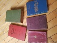All five books displayed on wood floor showing color and size variety