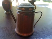 Miniature watering can made of brass with a handle and spout, showing some patina and signs of age.