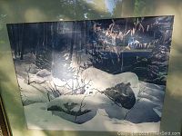 Framed watercolour painting depicting a snow-covered forest with rocks and trees, showing details of light and dark contrasts under glass.