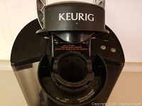 Top view of Keurig coffee maker showing pod holder and instruction labels.