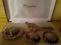 Five pieces including 3 pendants with a black and gold-tone checkerboard pattern, shown in a Mappins box