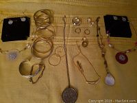 Full lot overview showing all bracelets, rings, necklaces, and earrings spread on a yellow fabric