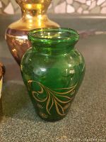 Green glass vase with gold-colored leaf design