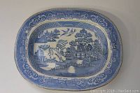 Top-down photo of oval ceramic platter showing blue willow pattern and decorative border.
