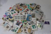 Large pile of unsorted worldwide postage stamps mostly attached to paper from envelopes.